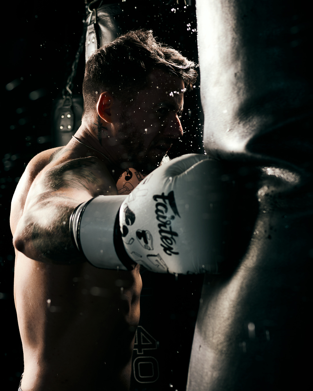 Muay Thai fighter kicks bag in dark gym